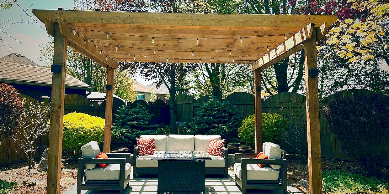 Cozy backyard pergola with seating and string lights.