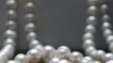 Close-up of elegant pearl necklaces against a dark background.