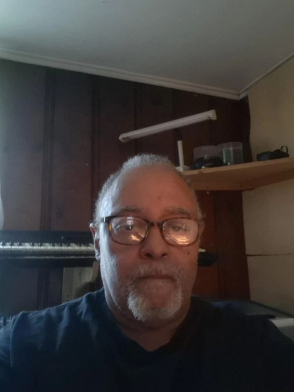Man wearing glasses in a room with wooden walls.