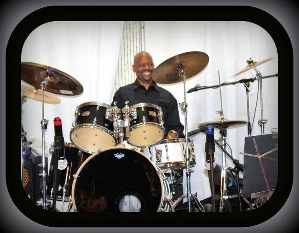 Man smiling while playing drums.