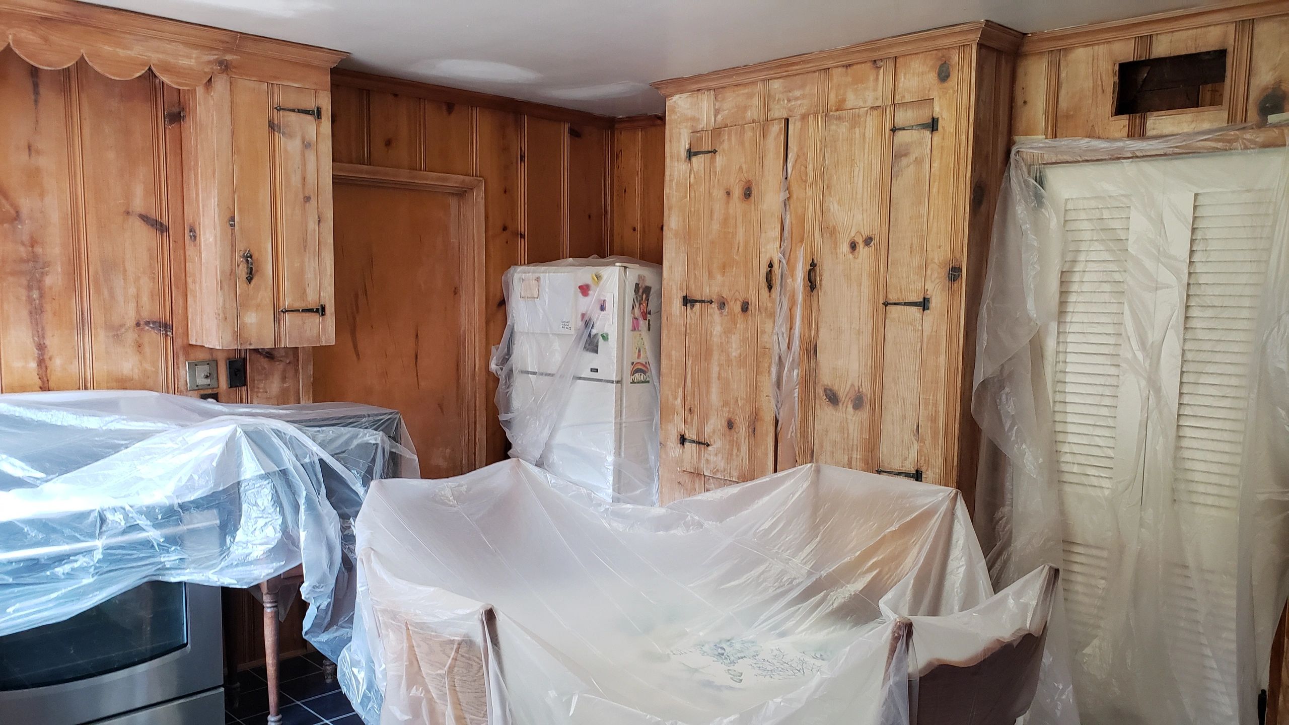Wood-paneled kitchen with covered furniture and appliances.