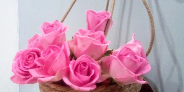 A basket filled with vibrant pink roses against a plain wall.