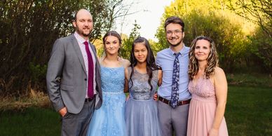 A group of five people dressed formally outdoors at sunset.