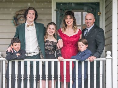 A family dressed formally, smiling on a porch.
