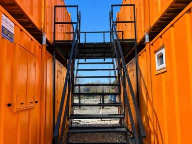 Orange shipping containers with a black metal staircase.