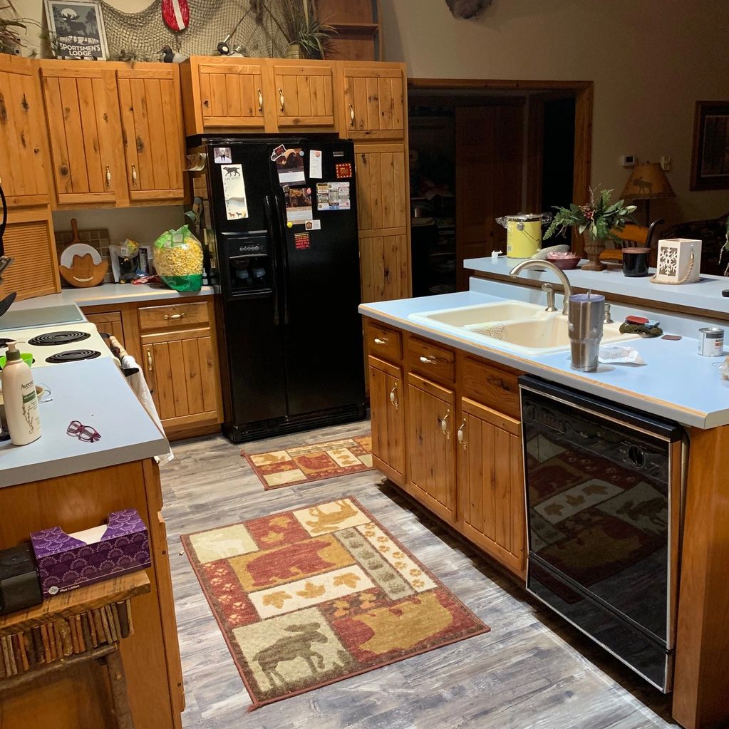 Rustic kitchen with wooden cabinets and wildlife-themed rugs.