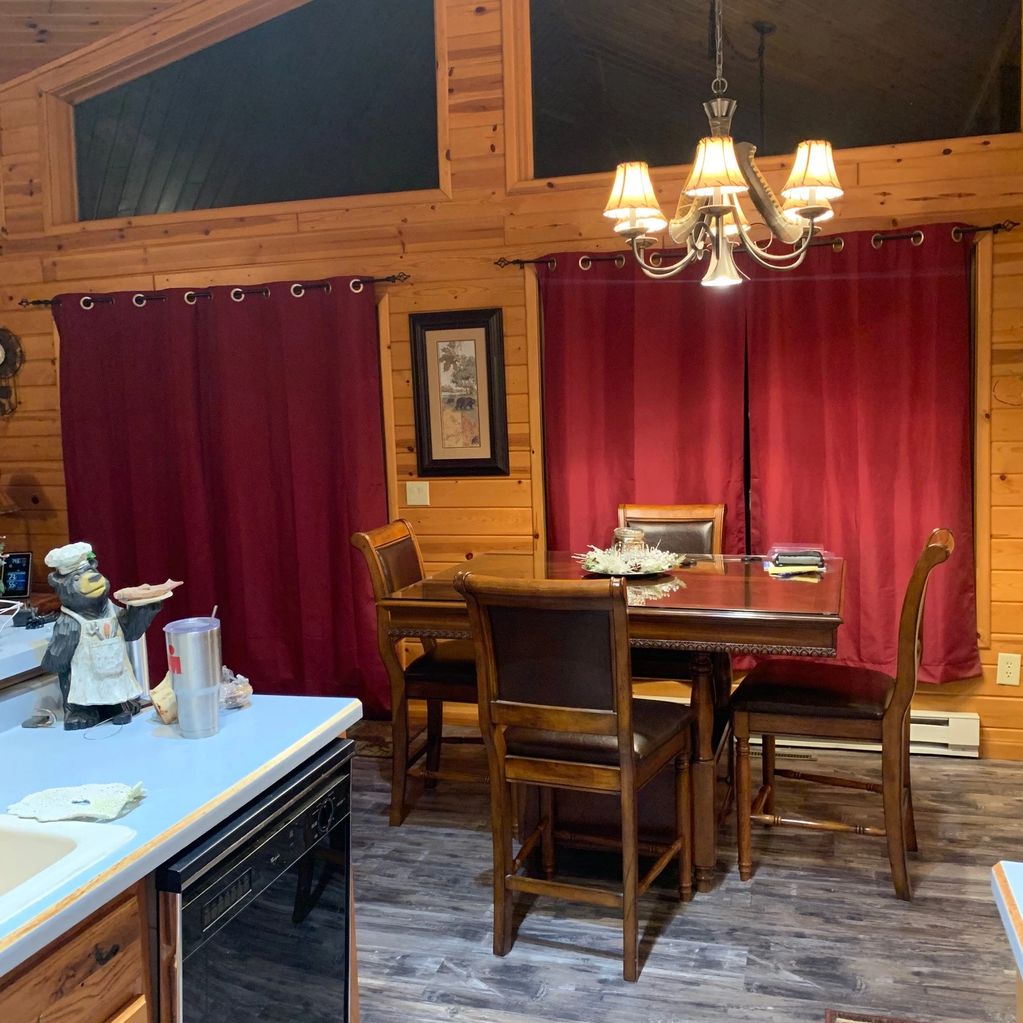 Cozy wooden kitchen dining area with red curtains.