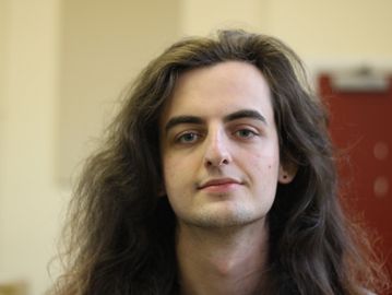 A white person with long brown hair against a slightly blurred background.