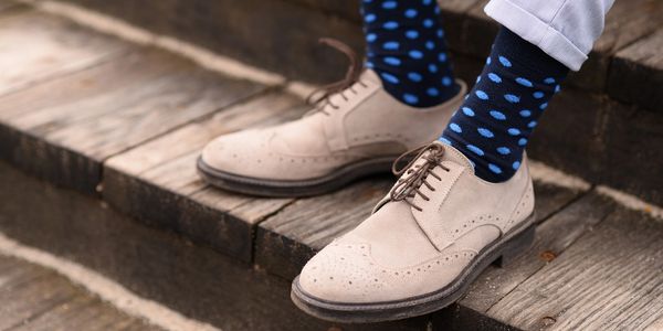 A man wearing shoes and dark blue dotted socks