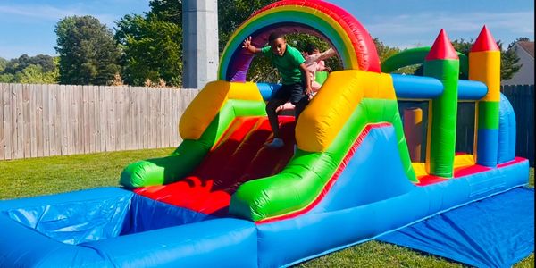 Kids enjoying a colorful inflatable bounce house with a slide outdoors.
