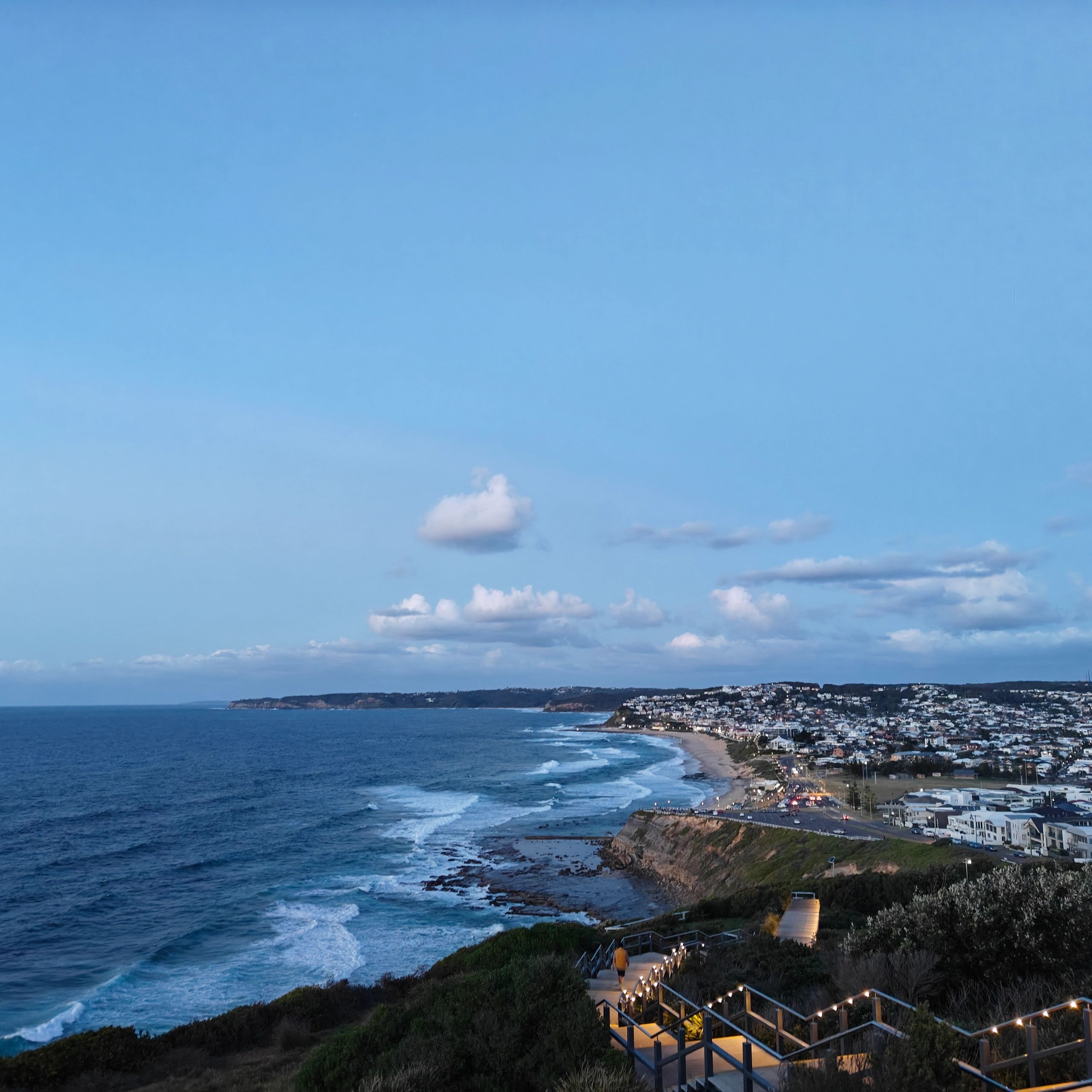 Coastal view of a beachside town and ocean at dusk.
