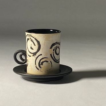 Off white ceramic espresso cup with spiral design and handle.  Satin black saucer. Gloss black liner