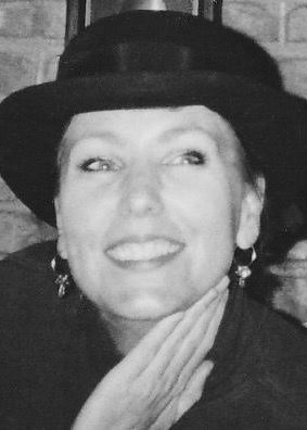Black and white portrait of a smiling woman wearing a hat and earrings.