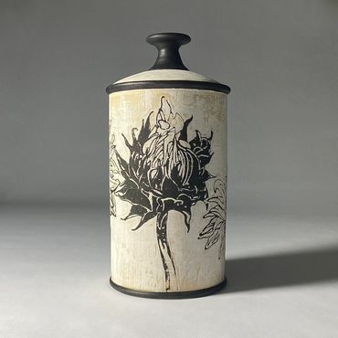 Tall off white ceramic jar with Sunflower design drawn in black.  Black knob, rim, and base.