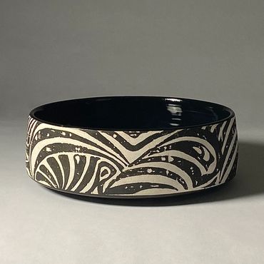 Low, wide ceramic serving bowl with black and white zebra stripe design.  Gloss black interior.