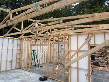 Wooden frame structure of a building under construction with ladders and tools inside.