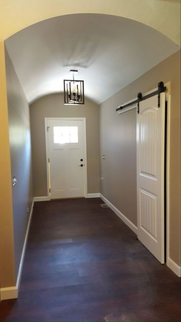 Narrow entryway with dark wooden floor and white barn door on the right.