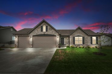 Modern single-story house with stone facade at sunset.