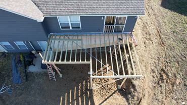 Wooden frame deck under construction behind a house.