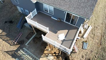 A newly constructed backyard deck attached to a house with white railings.