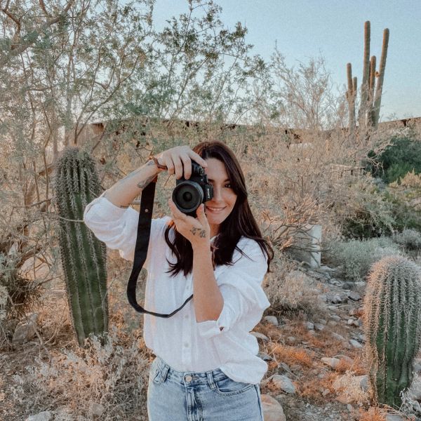 Woman taking a photo in a desert with cacti.