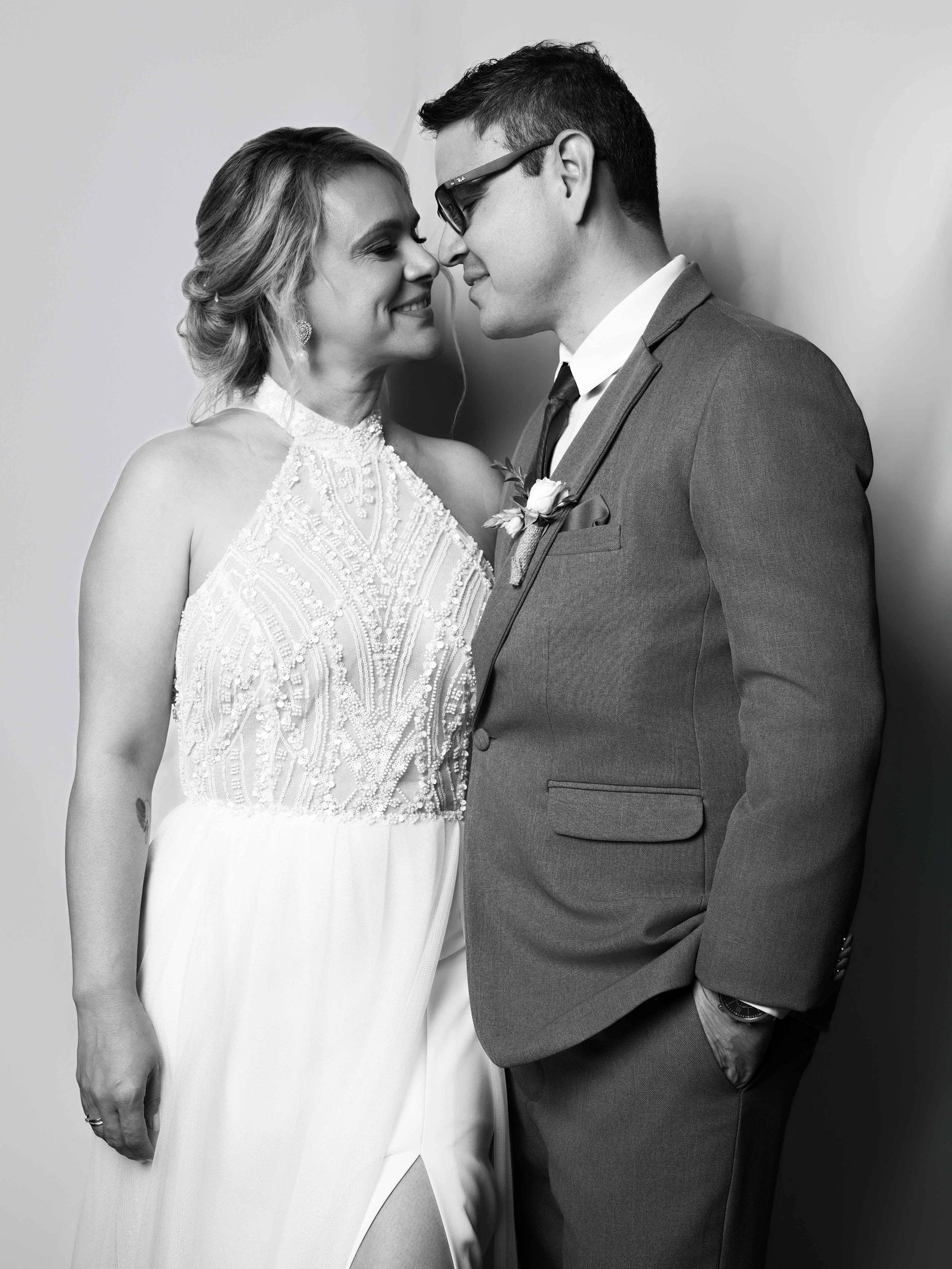 A bride and groom share a tender moment, smiling closely in black and white.