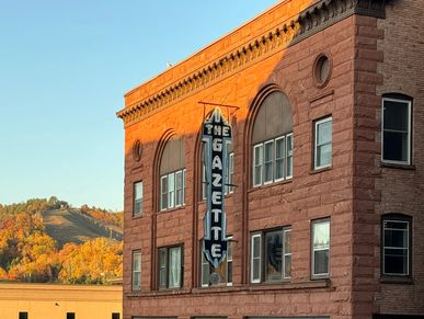 Historic Gazette building under clear sky at sunset.