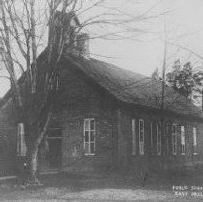 Old brick school building with leafless trees.