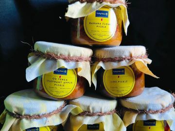 Stack of homemade pickle jars with yellow labels and cloth covers.