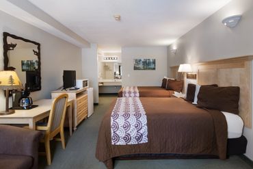 Cozy hotel room with two beds and rustic decor.