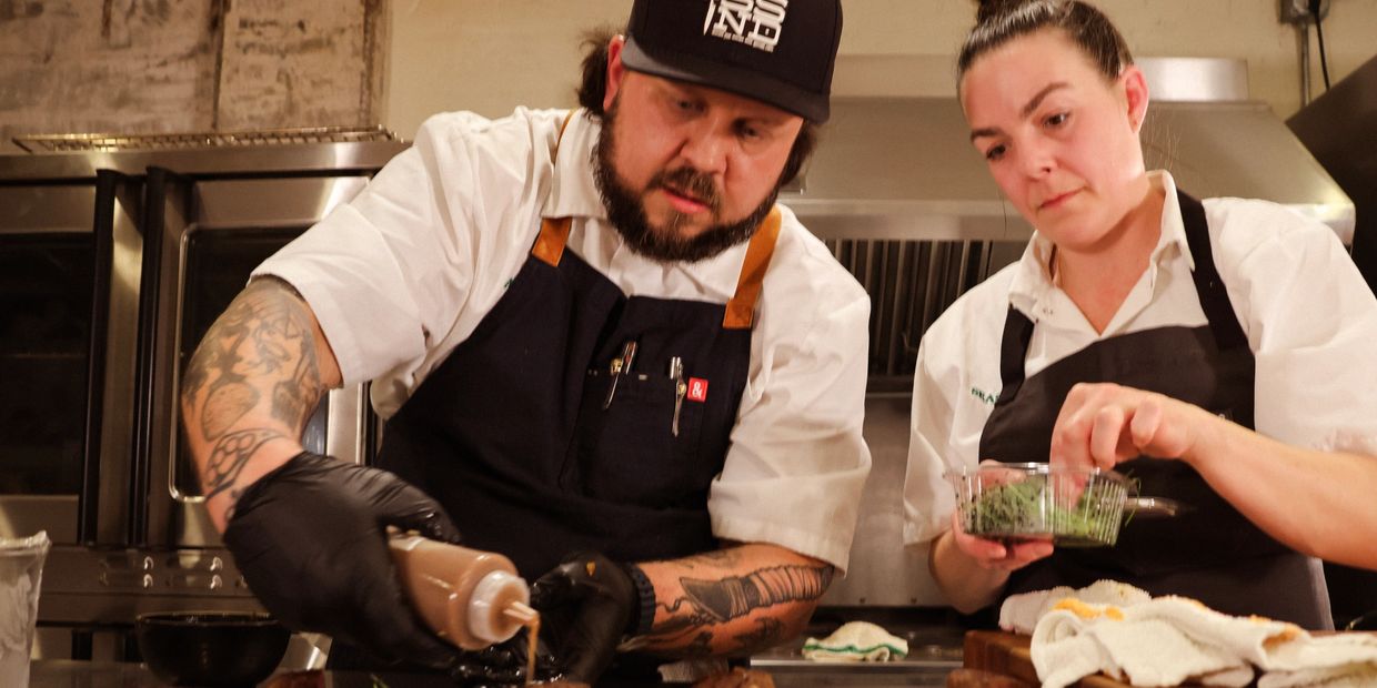 Two chefs preparing food together in the kitchen.