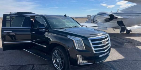 SUV negro Cadillac Parked Cerca de un jet privado.