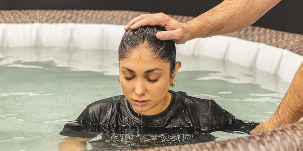 Persona siendo bautizada en agua.