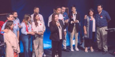 Group of people on stage, one speaking.