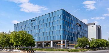 Modern office building with glass facade under a clear blue sky.