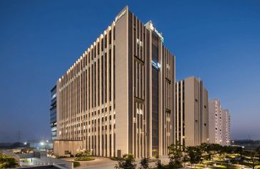 Modern multi-story building illuminated at dusk with clear sky.
