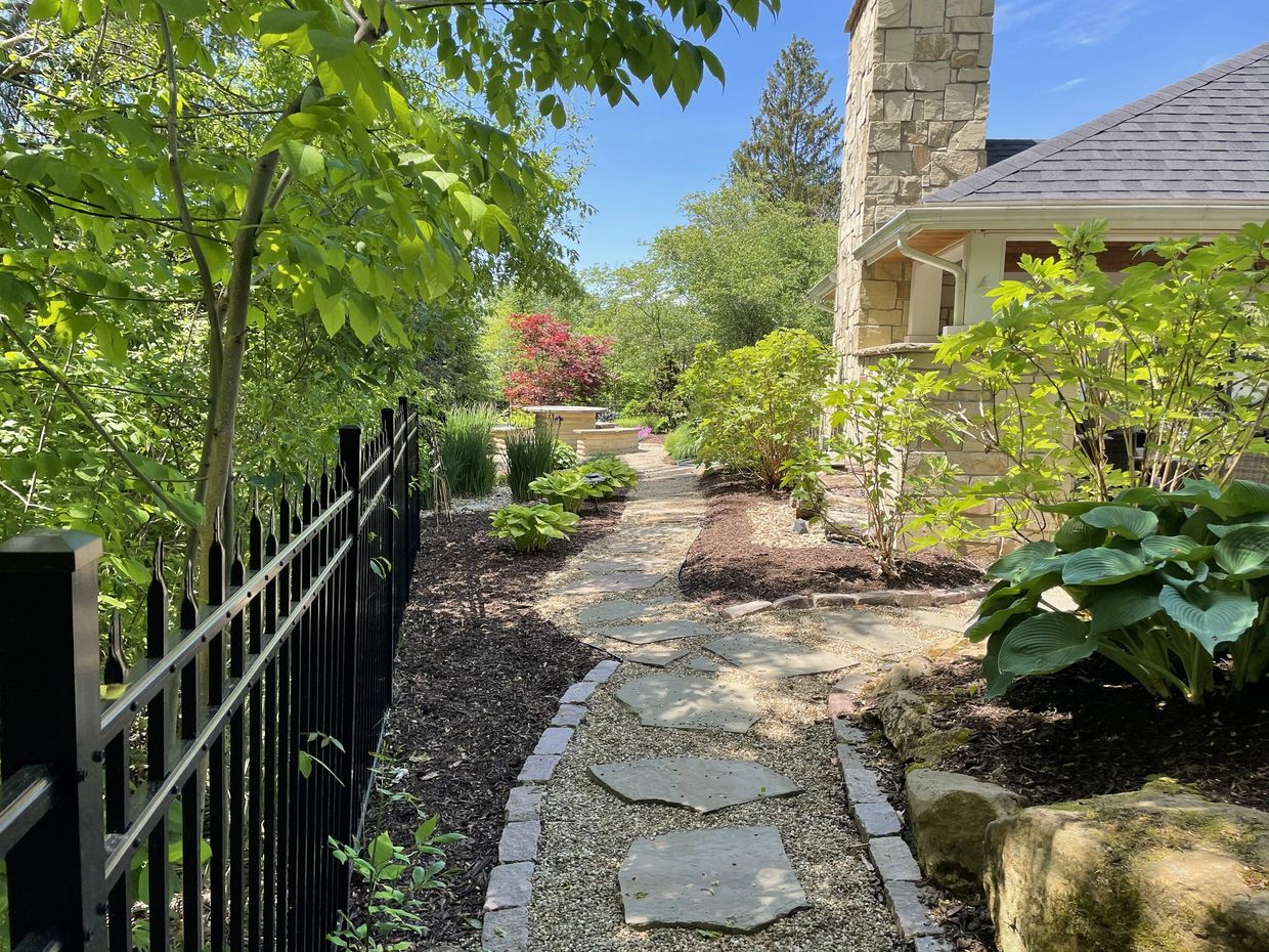 Stone pathway through a lush garden beside a Hudson Ohio house with a stone chimney.