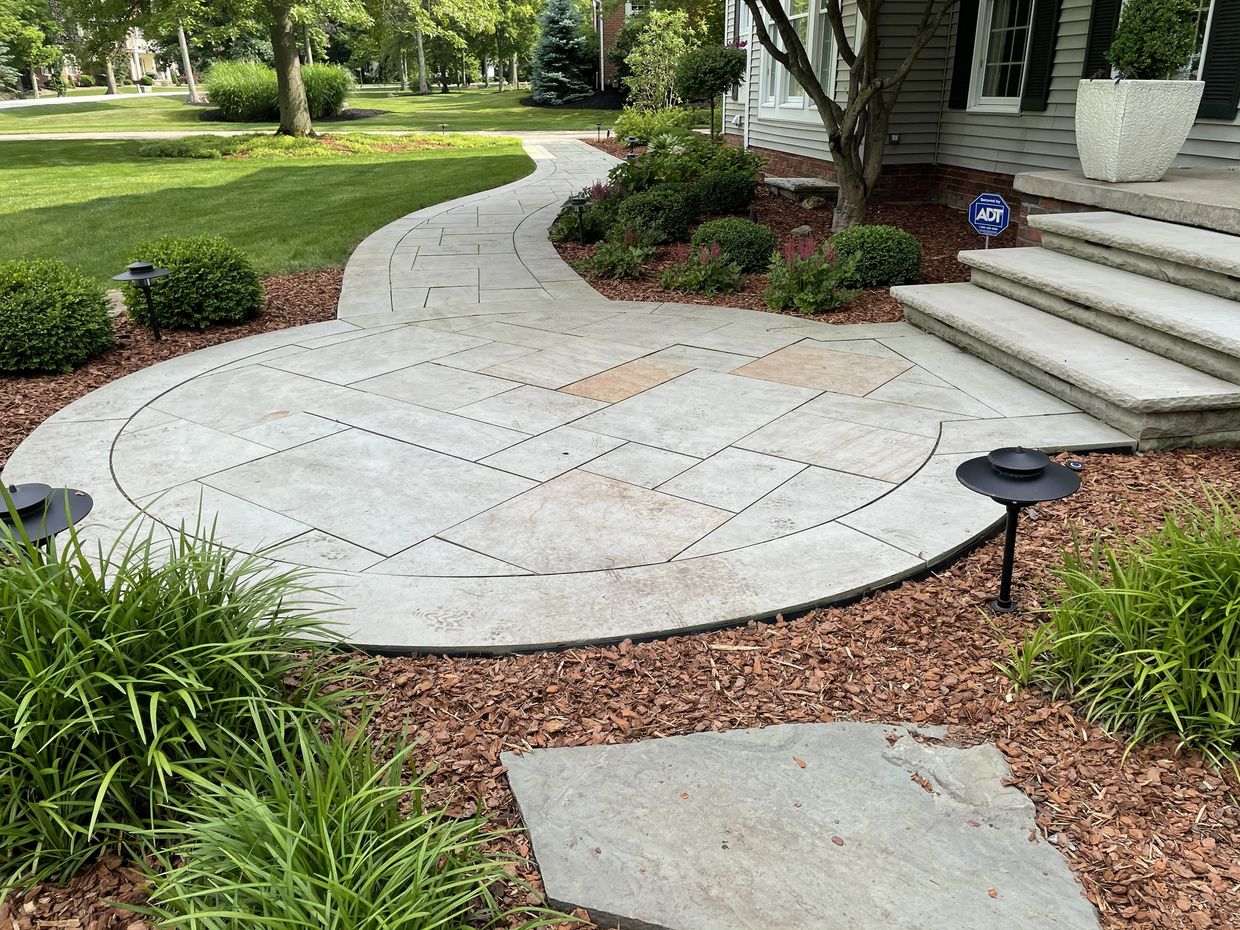 Curved stone pathway with landscaped garden and steps leading to a house.
