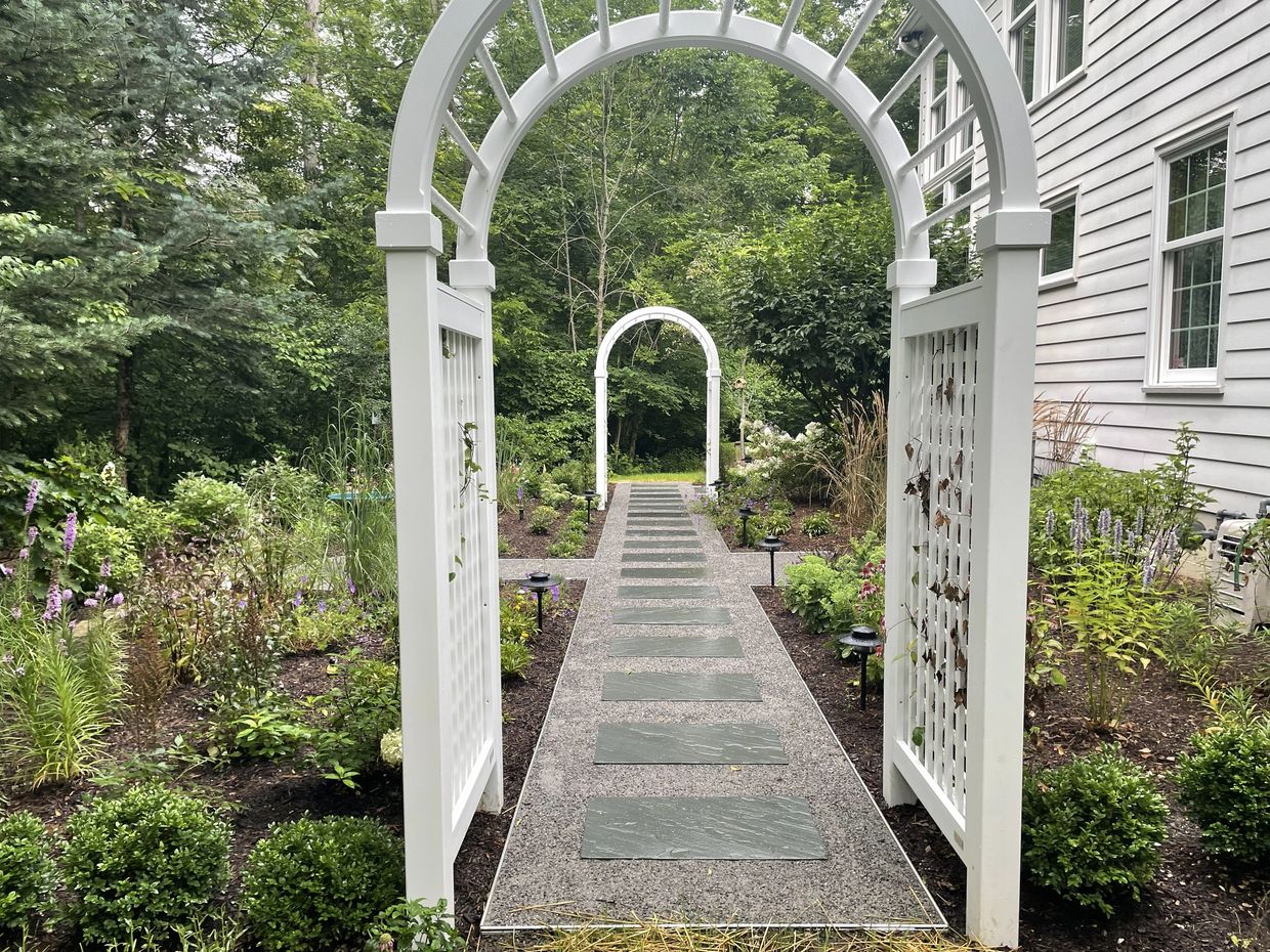 Garden path with white arches and greenery alongside a Richfield Ohio house.
