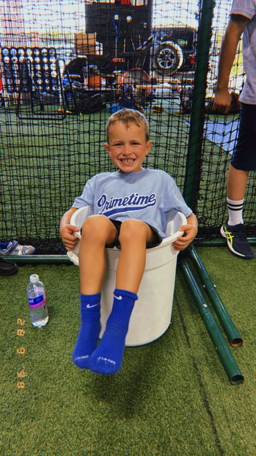 Boy smiling while sitting inside a large white bucket on artificial turf.