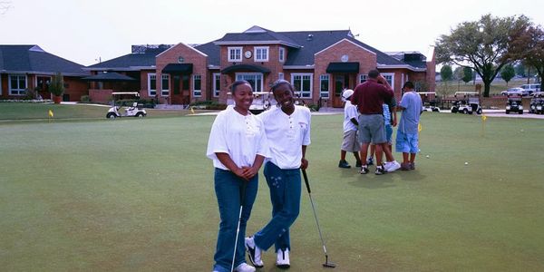 Two young teenagers are enjoying themselves after a 9-hole putting tournament.   