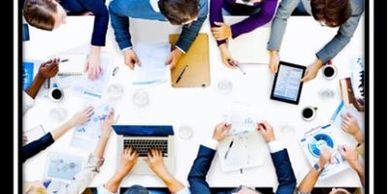 Photo of a office business meeting from above, only showing the table and peoples hands and arms