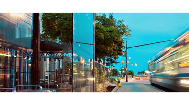 Photo of a bus driving in front of a large glass office/retail building