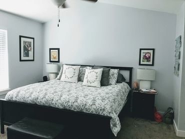 Cozy bedroom with a floral-patterned bed and framed wall art.