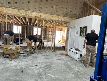 Workers renovating an indoor space with construction tools and materials.