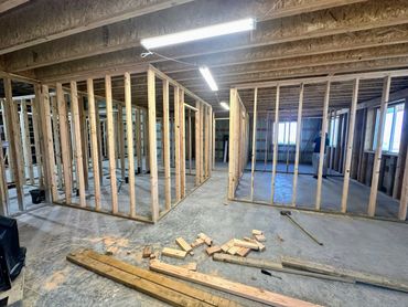 Interior framing of a room under construction with wooden studs and scattered lumber.