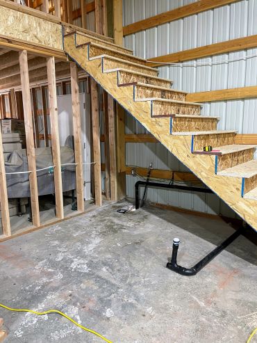 Unfinished staircase and exposed wooden frame in a construction area.