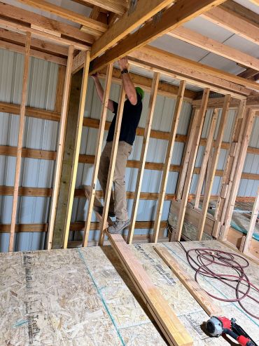 Person working on wooden framing inside a construction site.