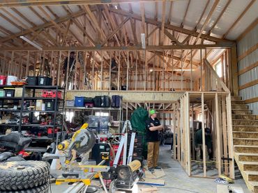 Interior view of a workshop with wooden framing and tools scattered around.