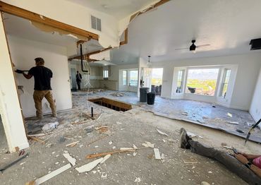 Home interior under renovation with workers and debris scattered.